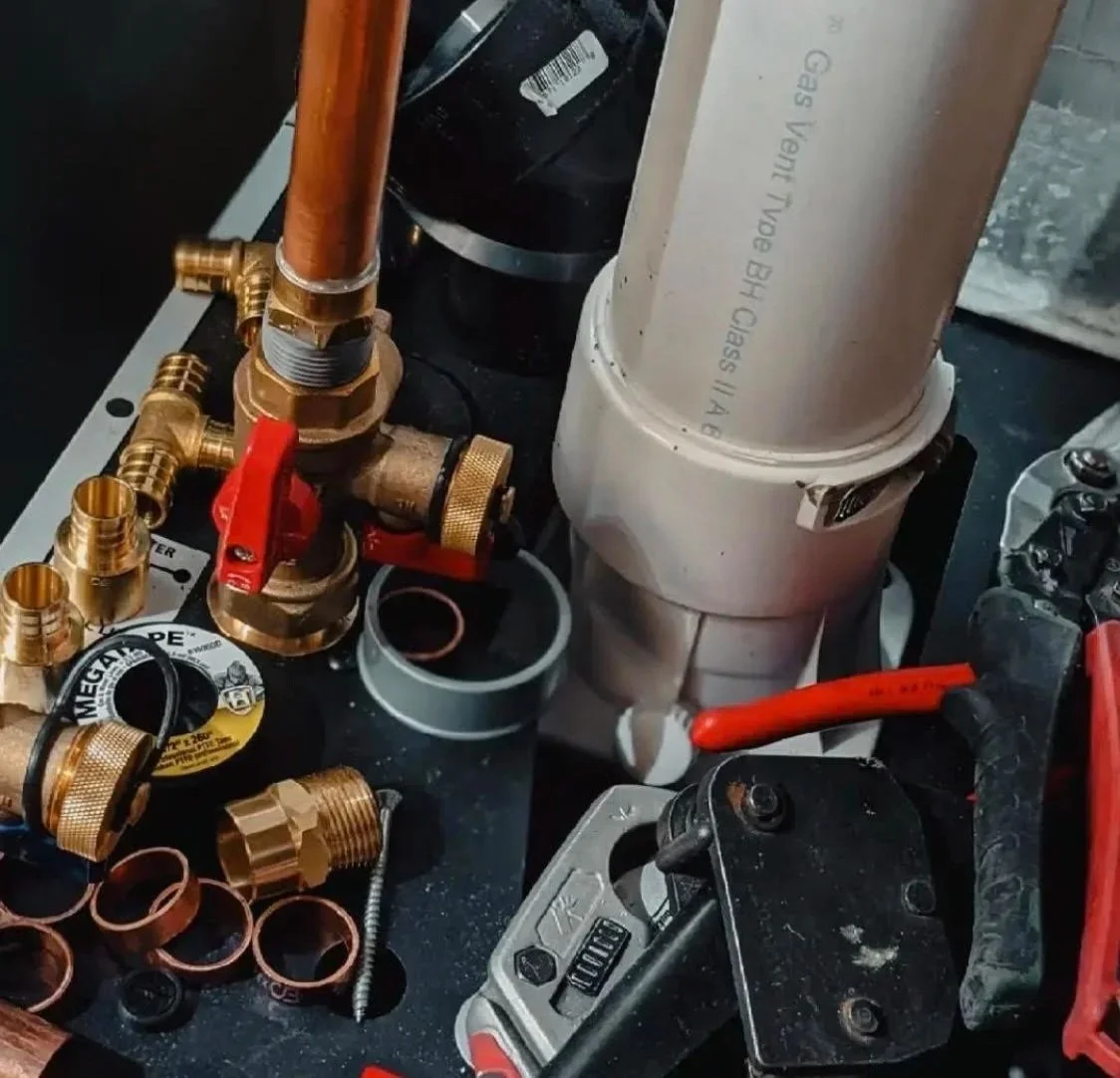 Copper pipe, brass fittings and red ball valves on a work surface